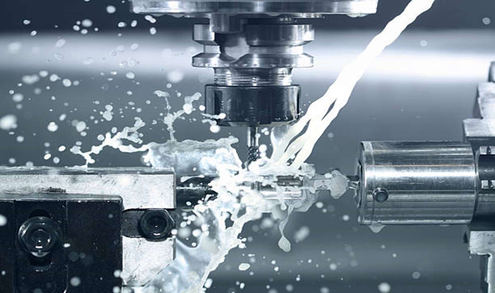 A CNC cutter removing metal under a stream of coolant during a finishing pass