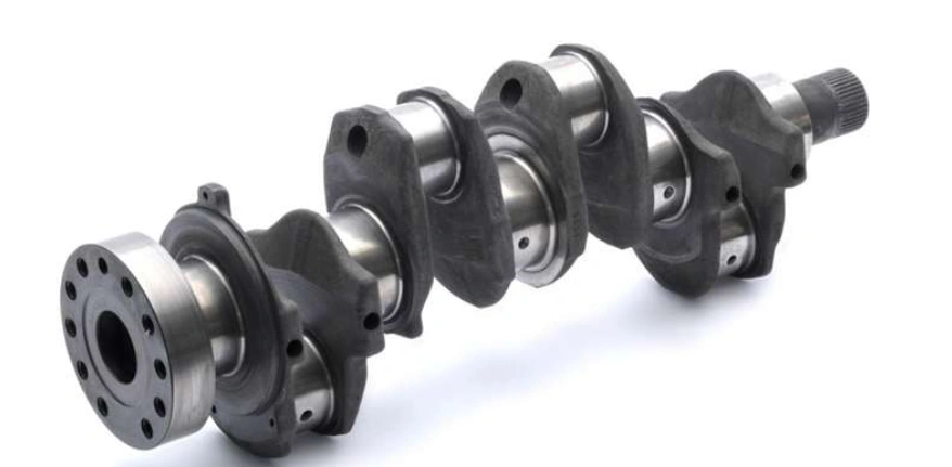 An image of a CNC-machined engine crankshaft with bearing journals and counterweights 
