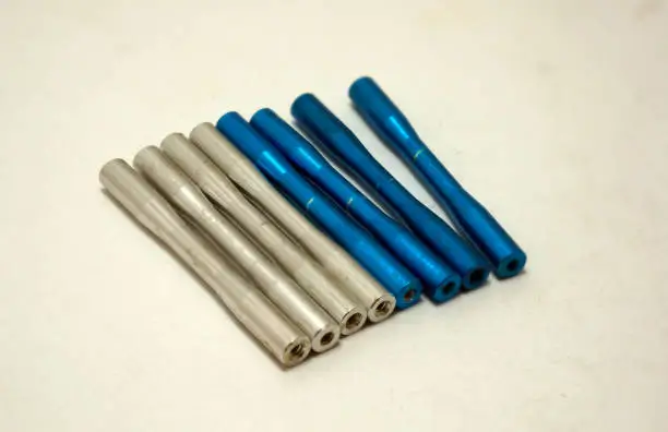 A comparison of raw titanium rods versus anodized blue titanium components, illustrating the physical transformation of the metal surface.