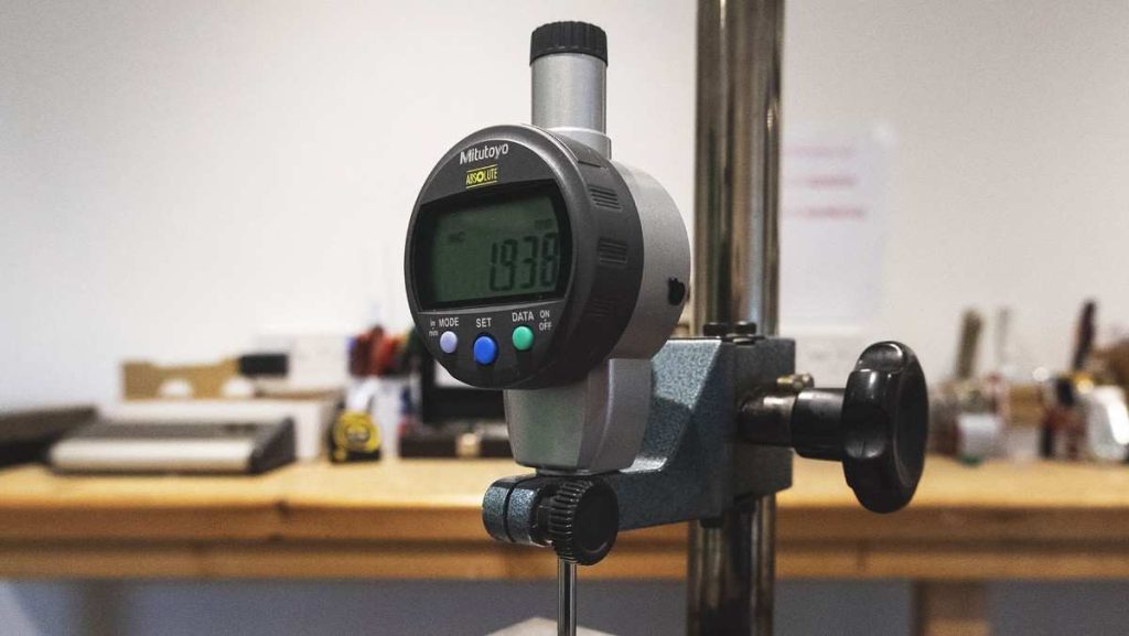 Digital dial indicator mounted on a stand.