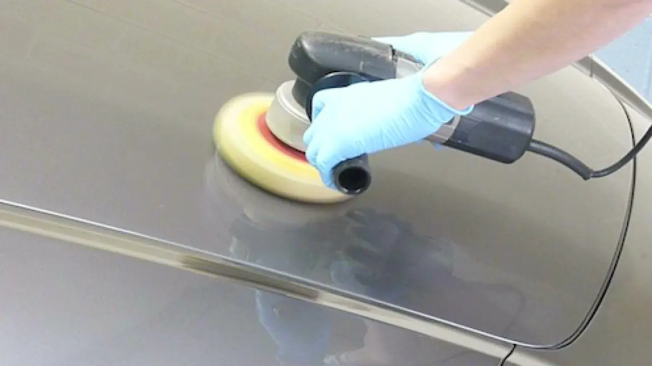 A polishing wheel spinning against a metal surface as a part is brought up to a glossy finish