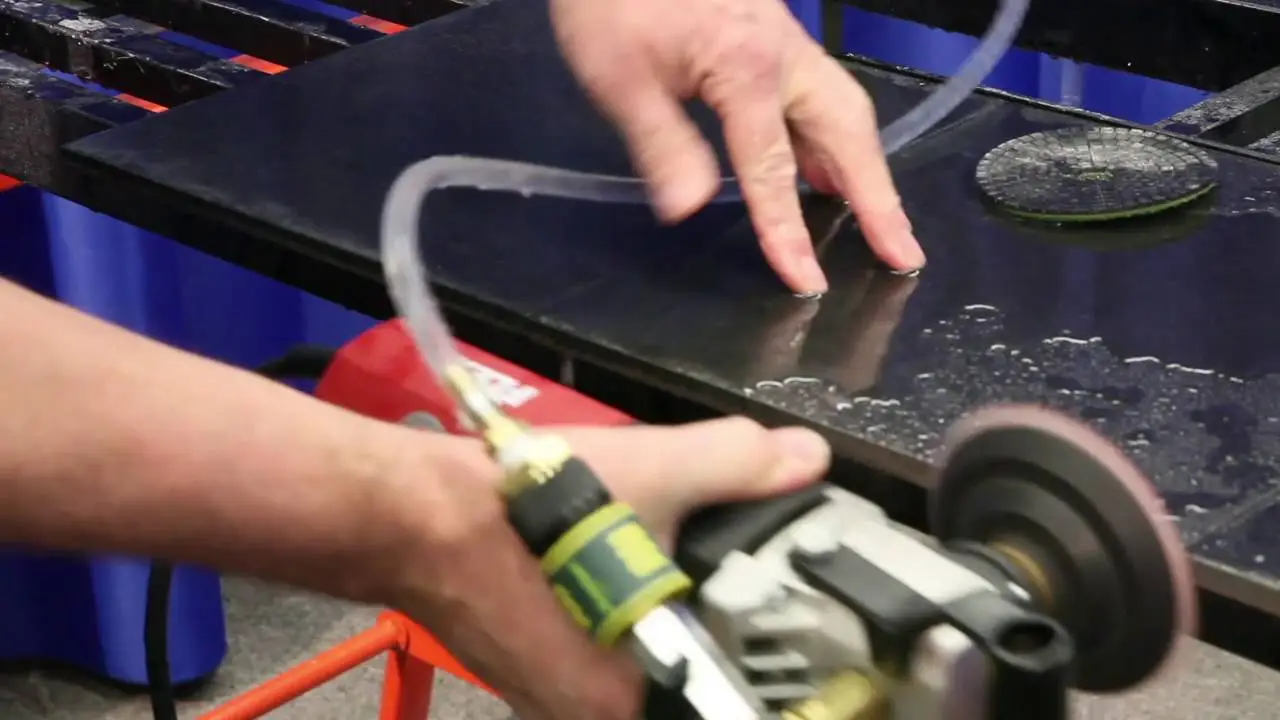 A hand rubbing abrasive paper across a wet metal surface to leave a fine sanded texture