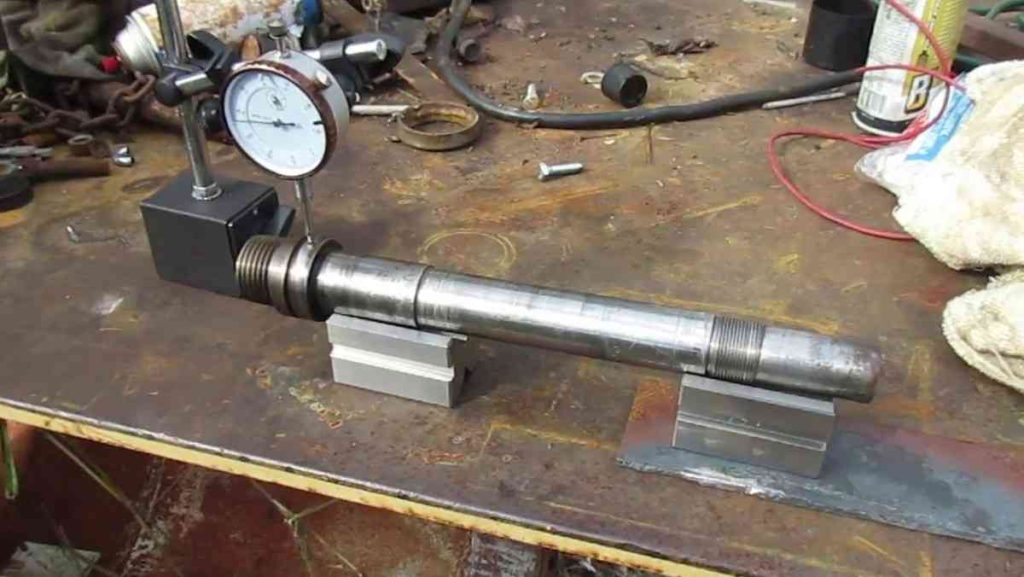 Dial indicator measuring deviation on a metal shaft.