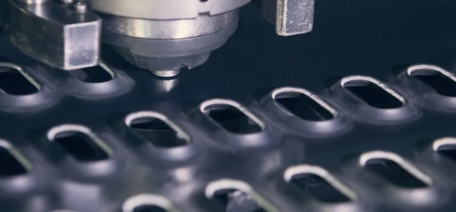 CNC turret punch press tool actively forming oblong counter-sunk holes in a metal sheet during high-precision sheet metal fabrication.