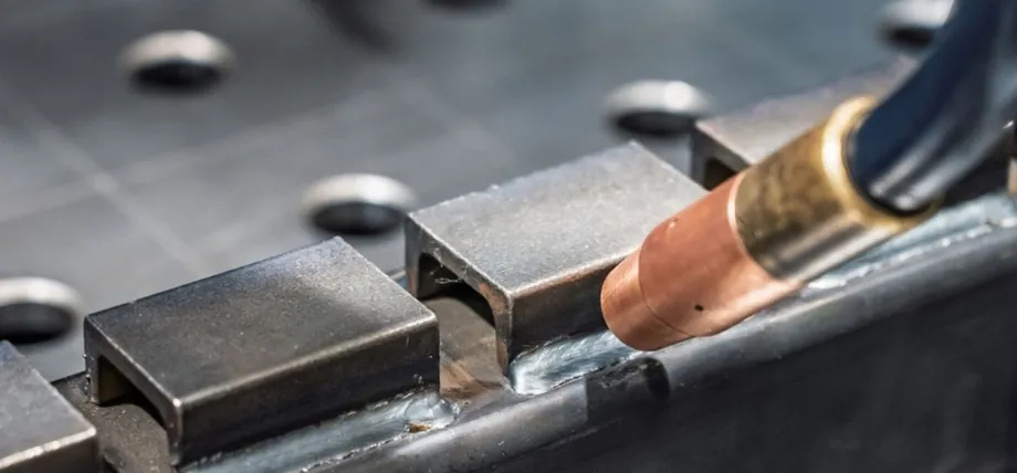 MIG welding torch depositing a clean bead to join folded steel brackets during sheet metal fabrication assembly.