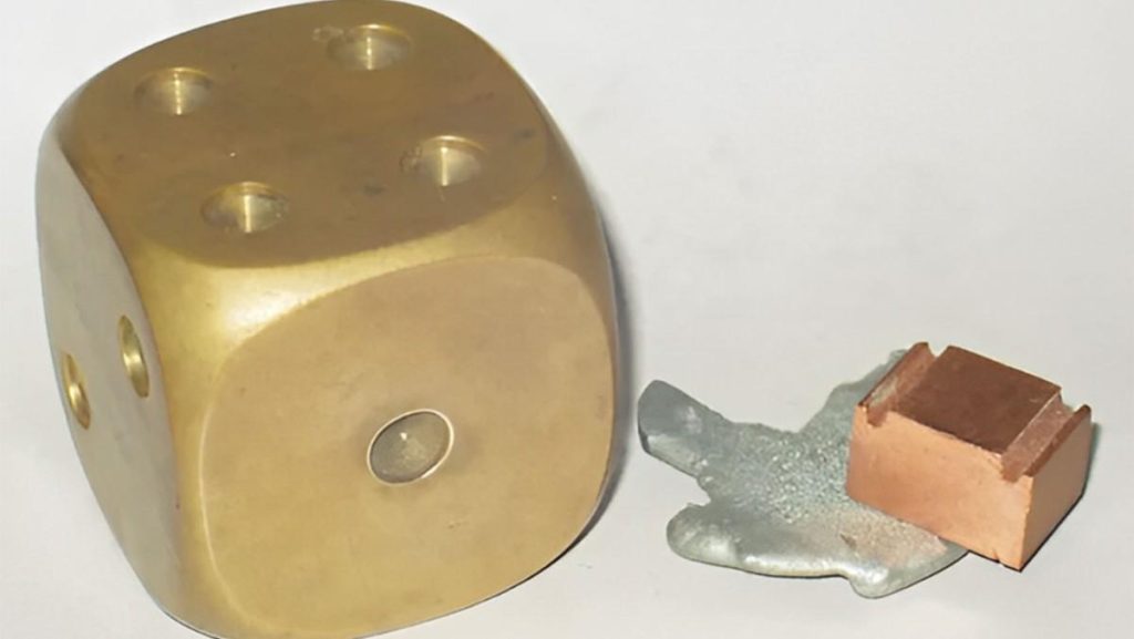 Large brass die next to silver and copper pieces.