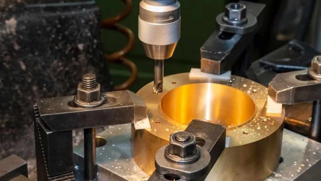 Drill press working on a brass component.