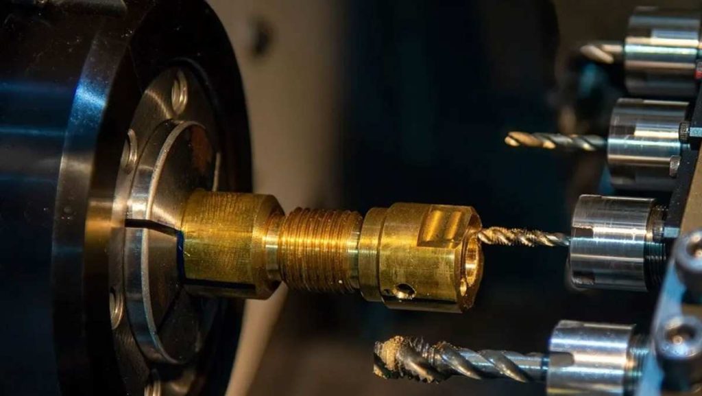 Close-up of a Swiss-style lathe machining a brass part with multiple tools.