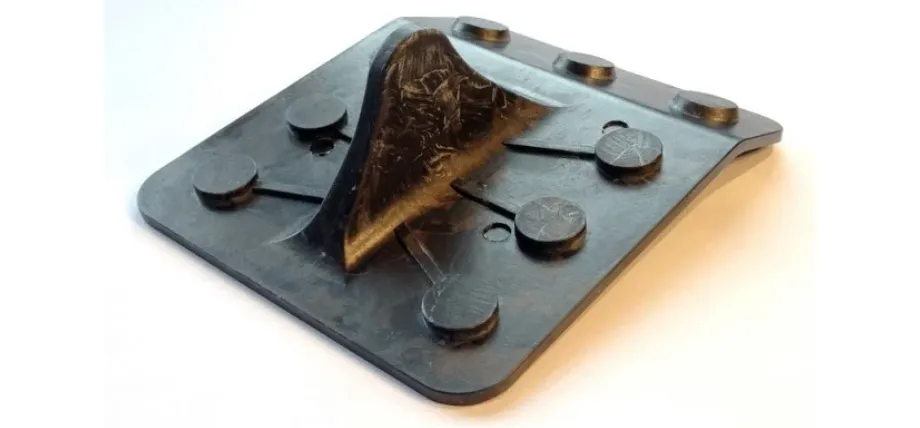 A durable black compression-molded composite plate featuring a raised central fin and circular reinforcement points.