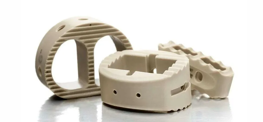 Three tan-colored PEEK plastic medical implants featuring complex ridged textures and precisely drilled holes for orthopedic use.
