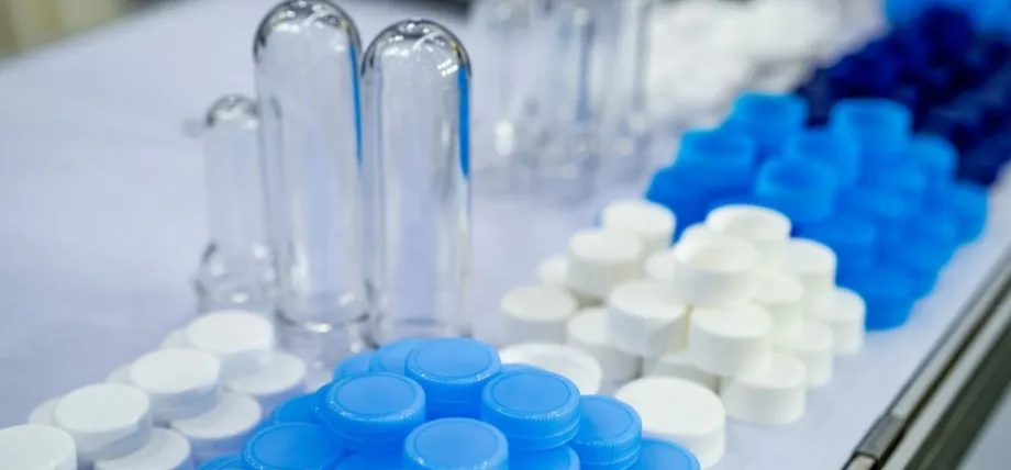 An assortment of injection-molded medical components, including clear test tubes and various blue and white plastic screw caps