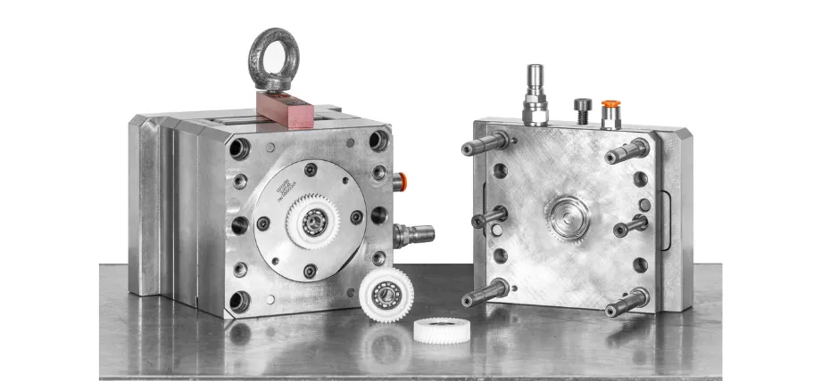 Two halves of a high-precision steel mold tool are shown next to the small white plastic gears they produce.