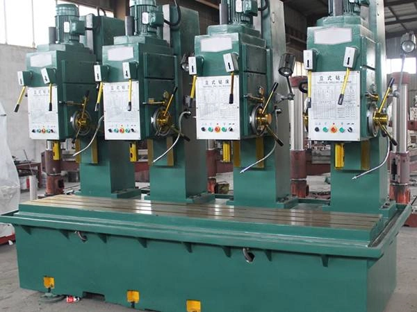 A large green drilling machine, which is an example of a gang drilling machine