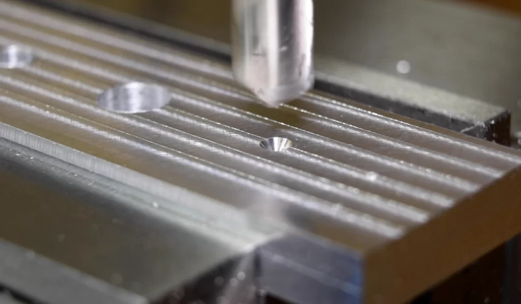A closeup of a spot drilling operation showing two ready holes and one being drilled on a metal plate 
