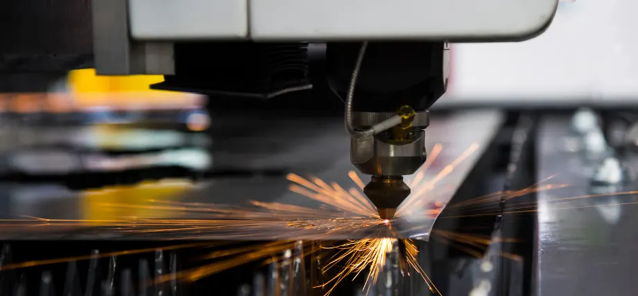 Laser cutting head emitting sparks while precisely cutting a metal sheet on an industrial machine.