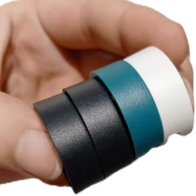 Four bead blasted ring samples held in one hand, showing a uniform matte texture in black, grey, teal and white