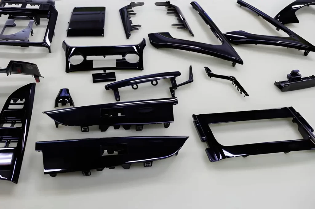 Glossy black automotive interior trim pieces placed on a workshop table.