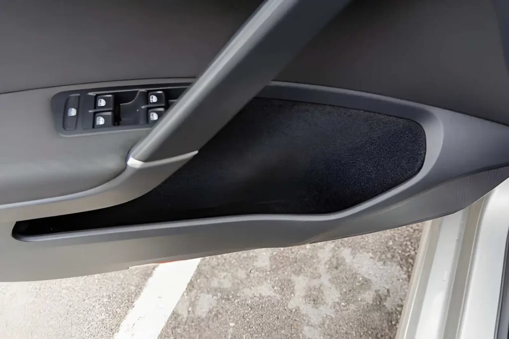 Modern car door interior panel with integrated storage compartment, typically produced using injection molding for automotive interiors.