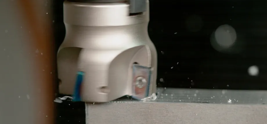 A face milling cutter in motion on a metal block, highlighting the material removal process and resulting finish.