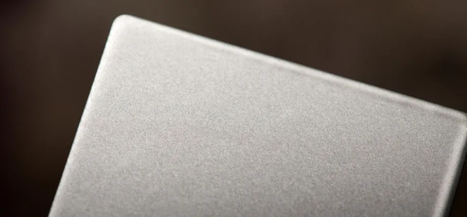 A macro view of a grey metal plate with a uniform, textured powder-coated protective finish.