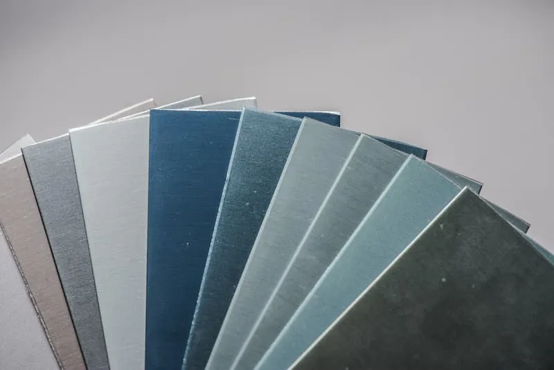 Different anodized aluminium sheet layers lying on each other in silver, blue, and other colors