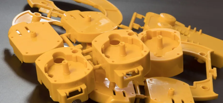 A cluster of yellow injection-molded plastic housings still attached to the runner system and gates after being removed from the mold.