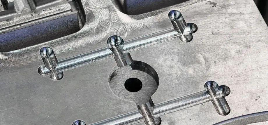 Close-up of a steel injection mold cavity featuring precision-milled channels and pins for shaping plastic parts.