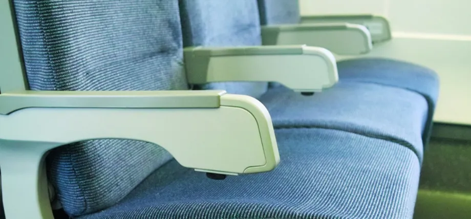 Blue fabric airplane seats showcasing durable, light-colored injection-molded plastic armrests and side panels.