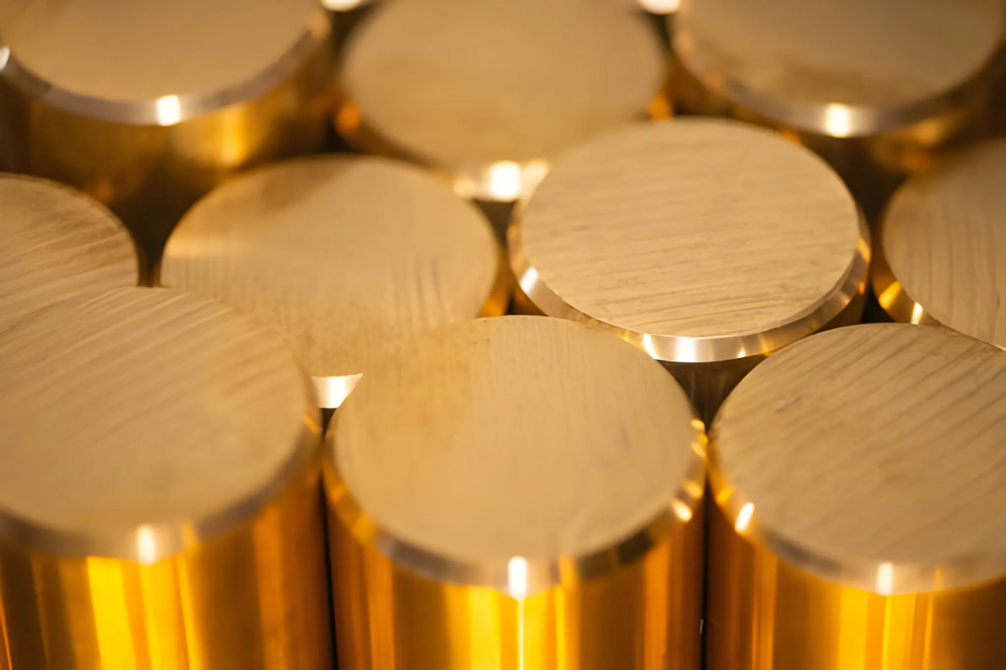 Bright brass bar stock arranged in a stack, its surfaces polished until they reflect light