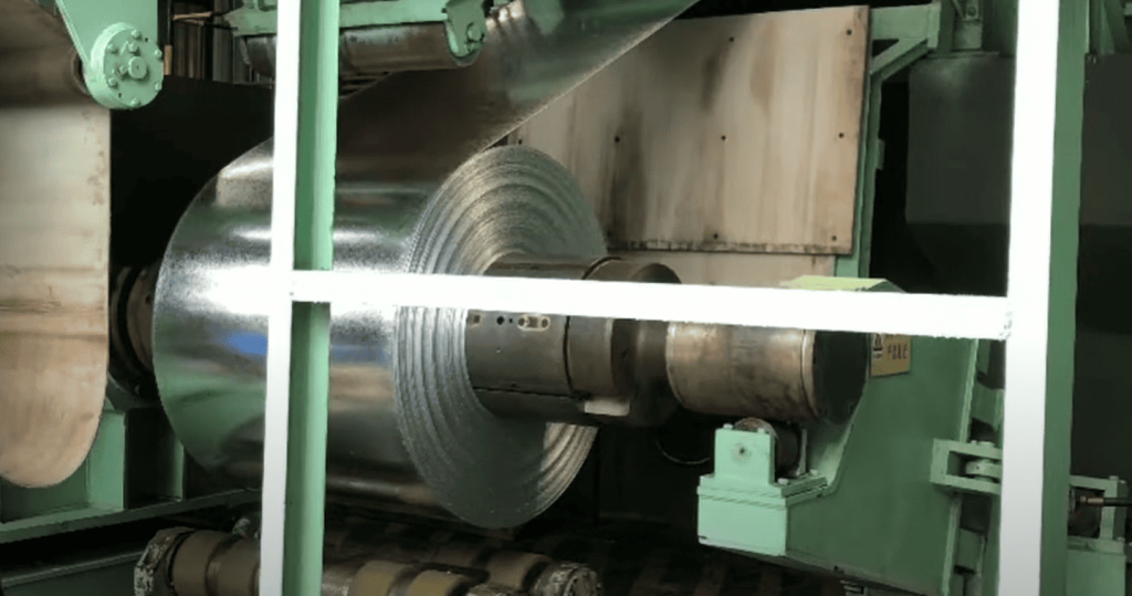 A close up view of galvanized metal sheet unrolling from coil 