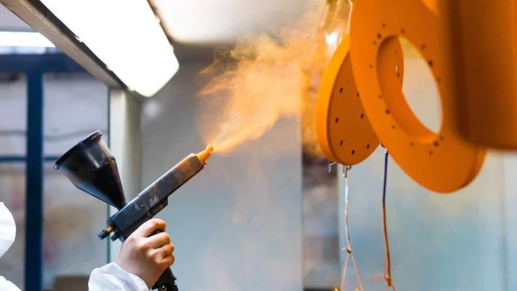 A person applying plasma spray coating, using a spray gun to apply a layer of protective material onto a surface.