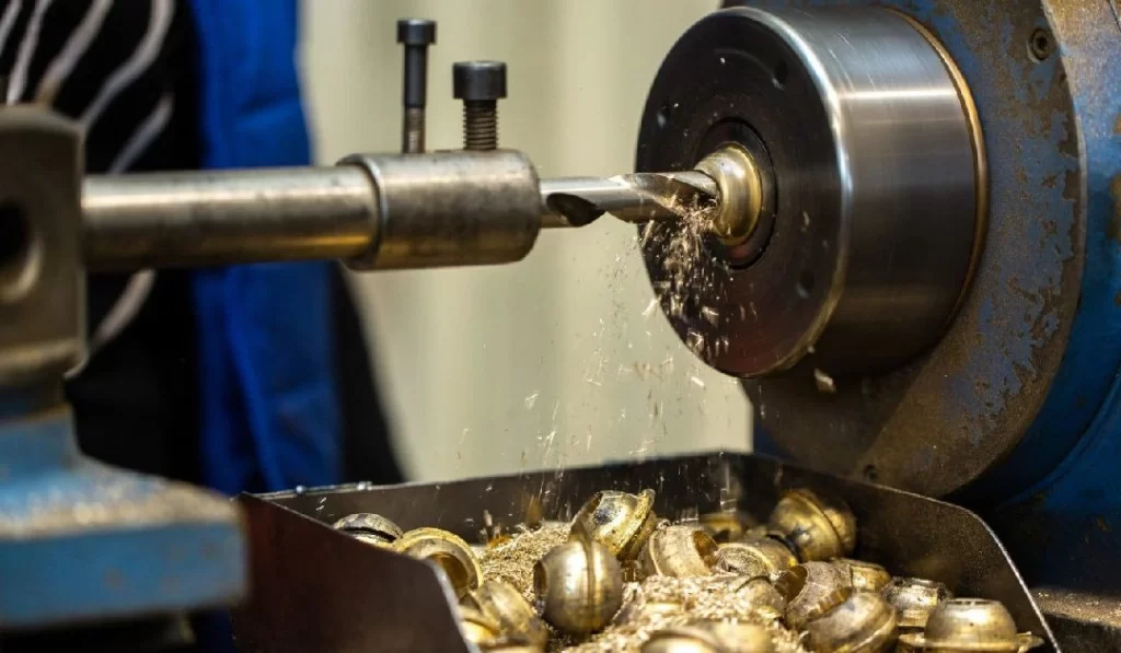 A drilling bit creating the hole on brass work attached to chuck of CNC lathe