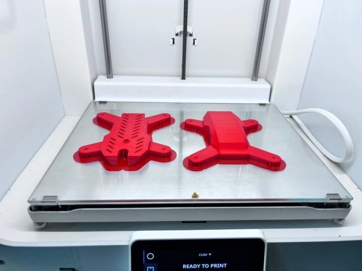 A close-up view of two drone enclosure sections lying on 3D printing bed 