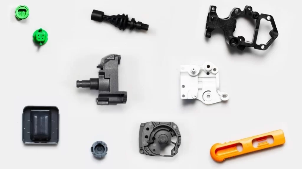 Injection molded automotive parts displayed, showcasing components such as brackets, clips, and housings for vehicle assembly.