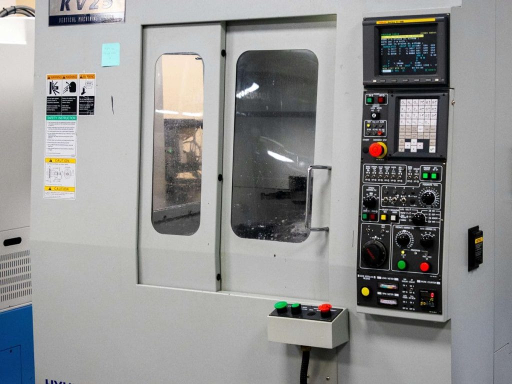 A lathe machine showing the door closed and a control panel 