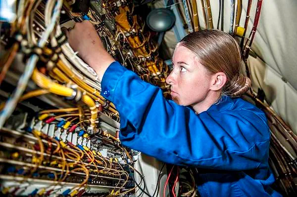 A skilled engineer working on intricate electronics wiring, demonstrating the importance of annealing for reliability in electrical components.