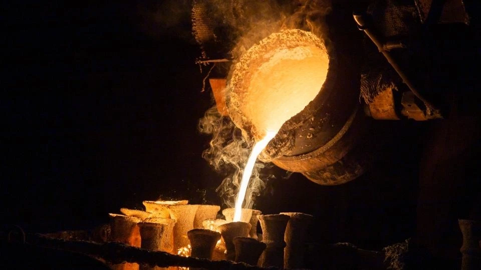 An image showing the high-pressure die casting process. Molten metal is being poured into a precisely designed die mold. The hot, liquid metal is filling the cavity of the die.