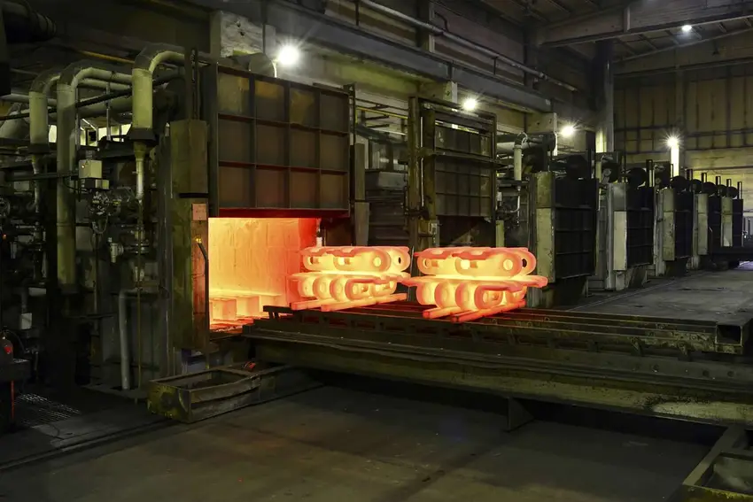 Industrial annealing furnace with glowing hot metal parts, showcasing the heat treatment process for improved strength and durability.