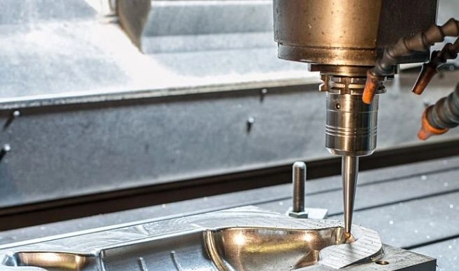 A closeup image of a milling machine forming a smooth contour in a metal block