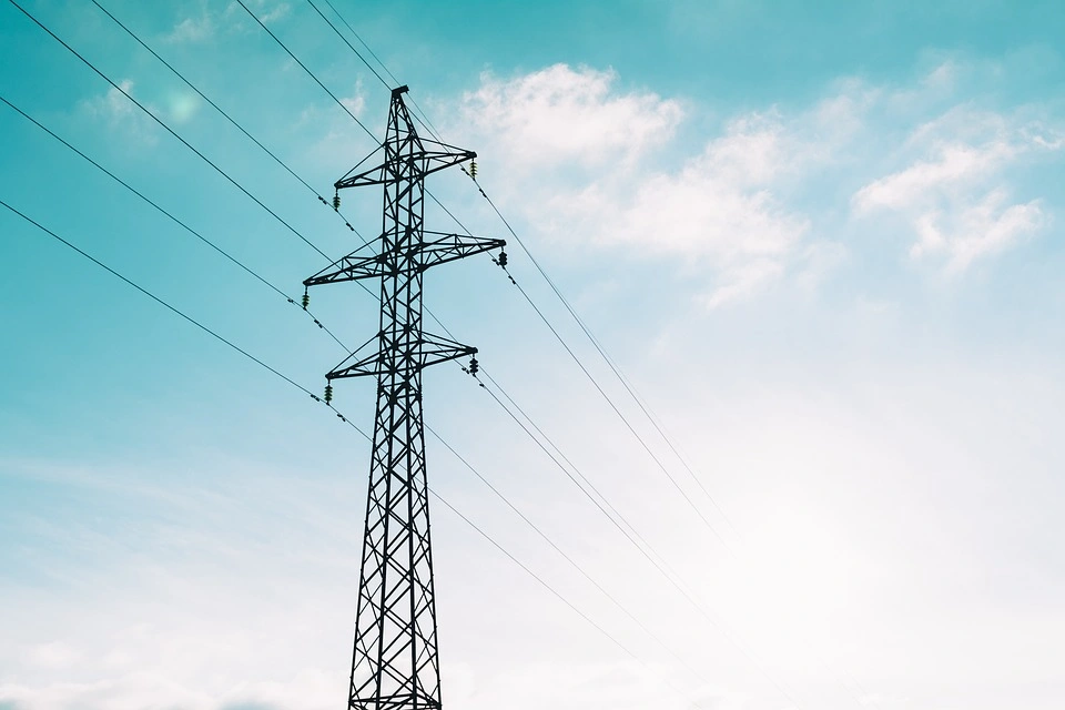 An image of seven power transmission lines connected to and running through a metallic tower