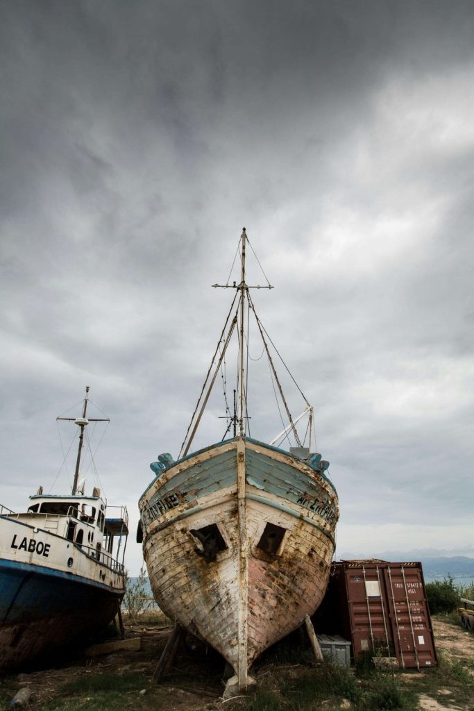 A previously brightly colored boat now covered in corrosion sitting on the seashore