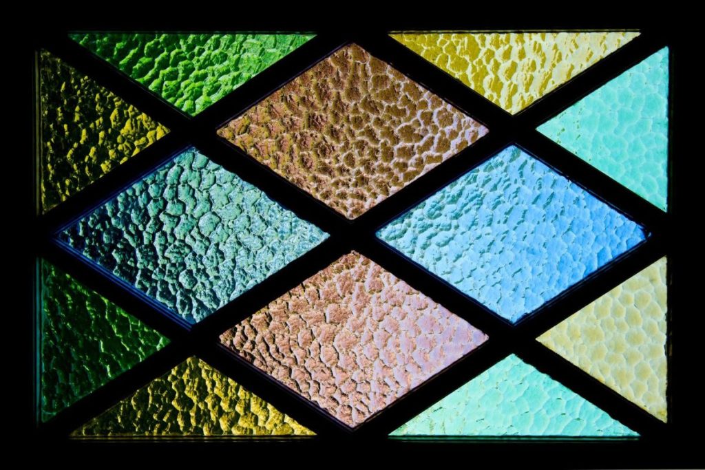 A glass panel divided into several diamond-shaped sections stained in different colors