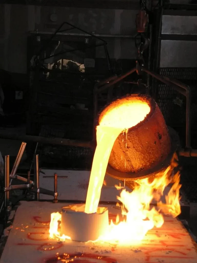 Flames as hot metal is poured from a larger container to a smaller one