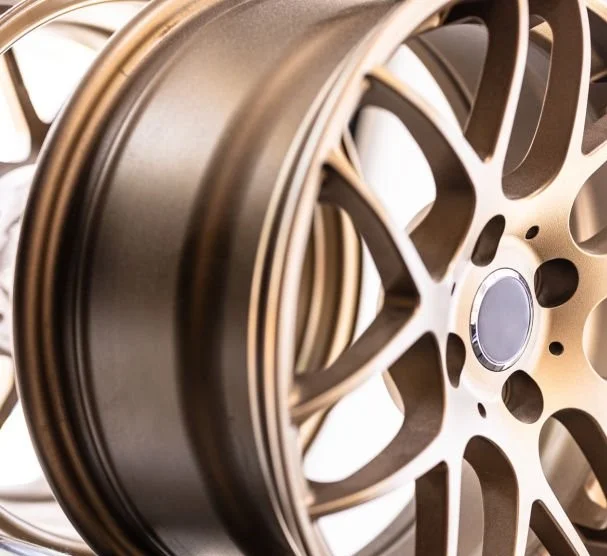 A section of a detailed car rim anodized to a light brown color