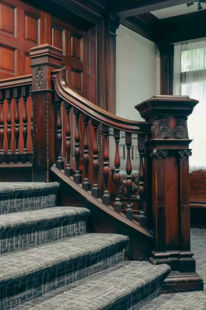 Dark brown wooden handrails and guardrails with well-defined curves and surfaces inside a house with a grey floor