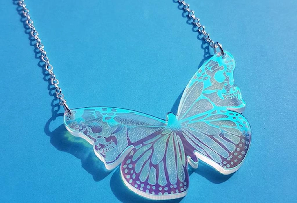 A butterfly-shaped acrylic necklace with a silver chain, showing the capabilities of laser cutters