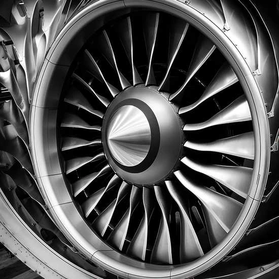 An image of carbon fiber airplane engine blades showing intricately shaped blades attached to an outer outline and centered shiny axis.