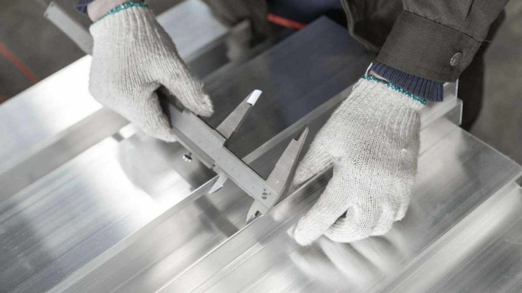 An image of a person inspecting the quality of an aluminum extruded part. The individual checks the part’s quality to verify it meets the required standards