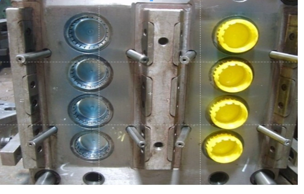 A close-up view of two mold halves showing cavity and yellow-colored bottle caps 