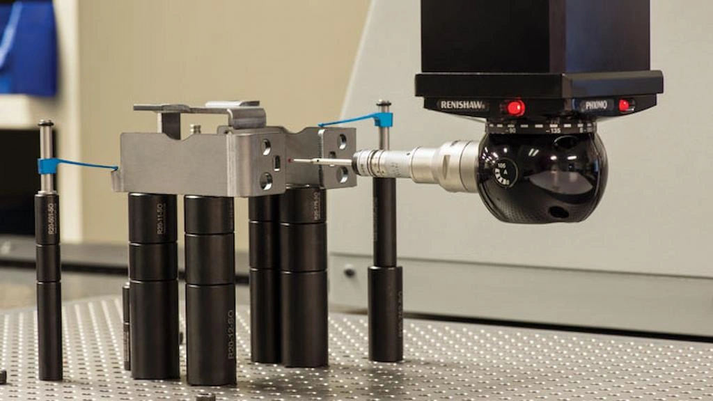 A close-up image of a CMM machine performing measurement of stamped stainless part with the probe.